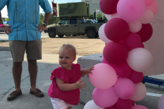 A father looking at his child playing with some decorative balloons
