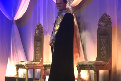 A man in some robes standing between two chairs