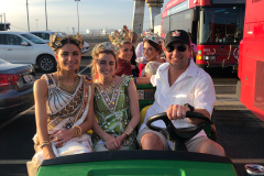 Two duchesses in the front seat of a club car next to the driver all smiling at the camera